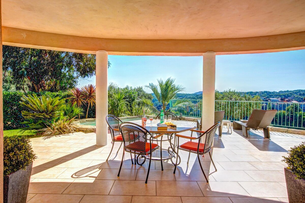 A patio with a table and chairs and a view