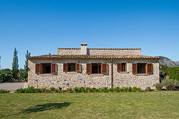 A stone house with brown shutters on the windows