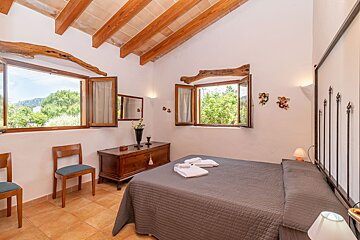 A bedroom with a bed a dresser and two windows
