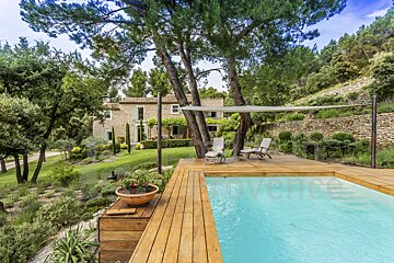 A swimming pool is surrounded by trees and a wooden deck