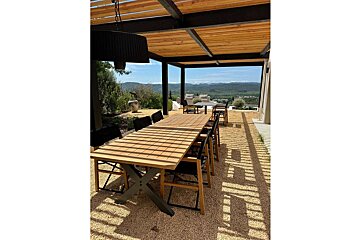 A wooden table and chairs under a wooden pergola
