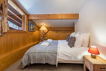 A bedroom with a bed and a lamp on the nightstand
