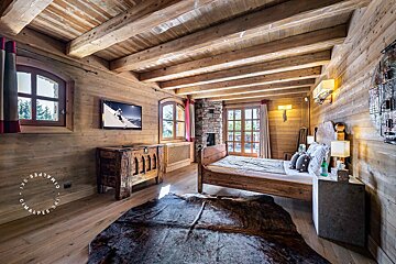 A bedroom with a cowhide rug and a flat screen tv