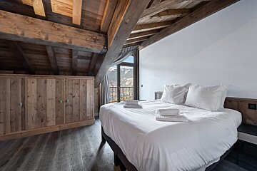 A bedroom with a bed and a window with mountains in the background