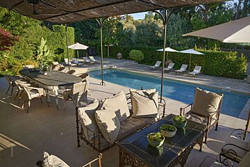 A large swimming pool is surrounded by chairs and umbrellas