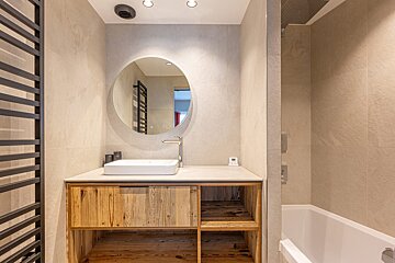 A bathroom with a sink and a round mirror