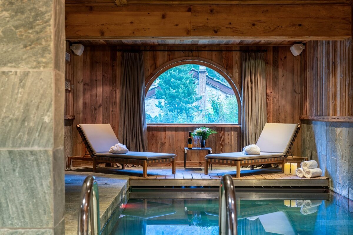 A wooden room with a swimming pool and chairs