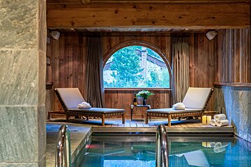 A wooden room with a swimming pool and chairs