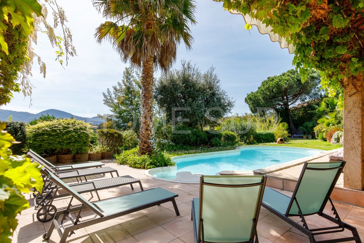 A swimming pool is surrounded by lawn chairs and palm trees