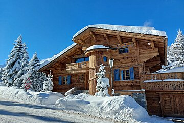 A large wooden house is covered in snow