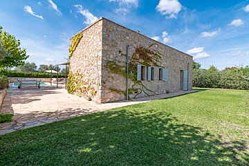 A stone house with a swimming pool in the background