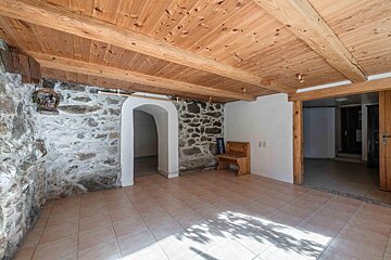 An empty room with a stone wall and wooden beams