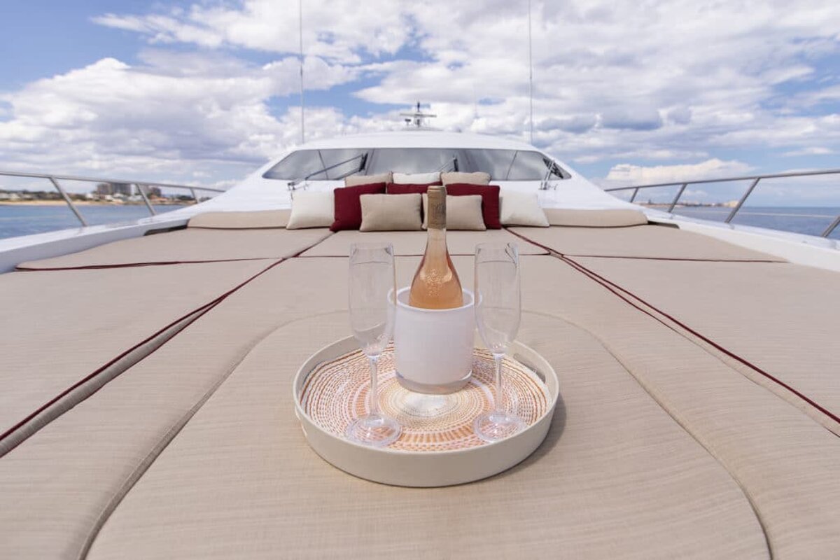 A bottle of wine sits on a tray on the deck of a boat