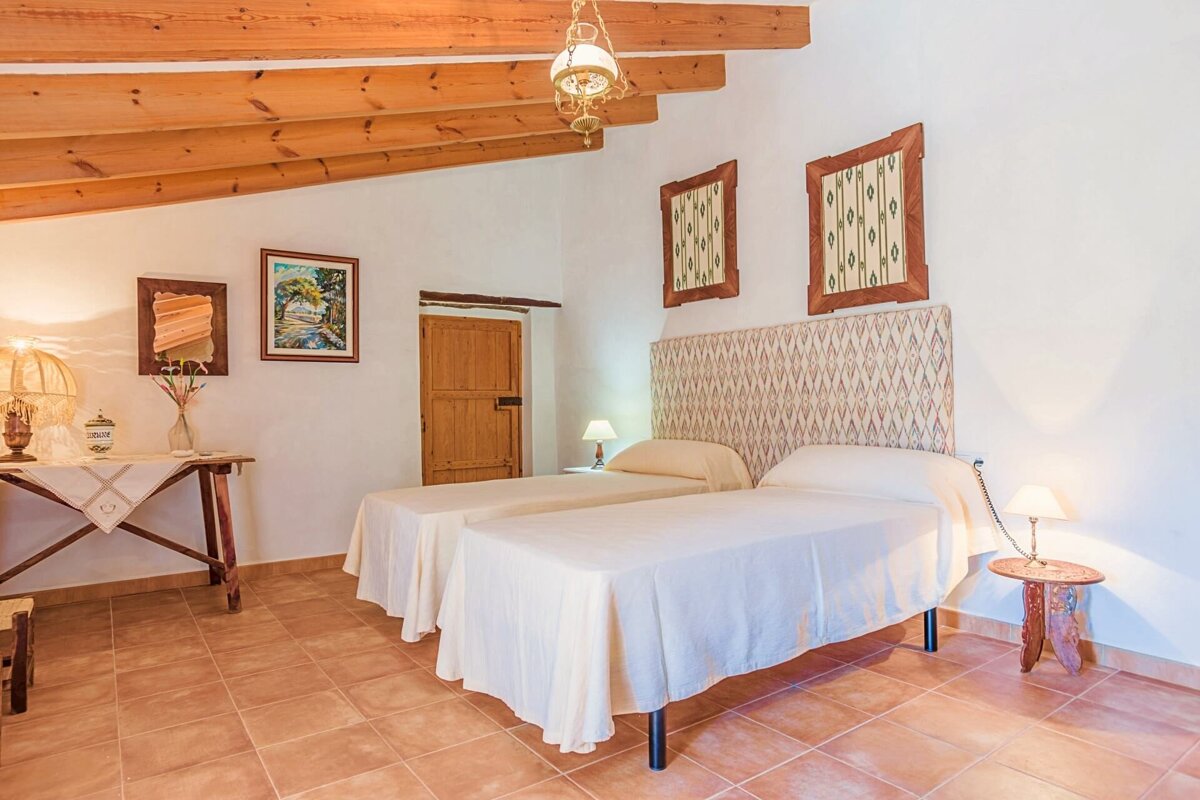 A bedroom with two beds and two paintings on the wall