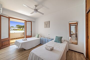 A bedroom with two beds and a ceiling fan