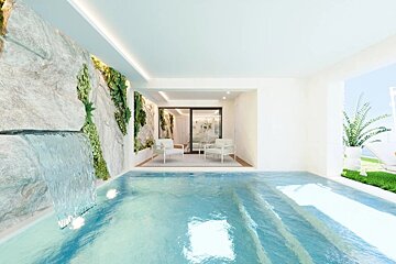 A modern indoor pool with a stone wall waterfall, green plants, and a lounge area with armchairs in the background.