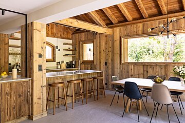 A kitchen and dining area with wooden walls and stools