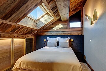 A bedroom with a bed and a skylight in the ceiling