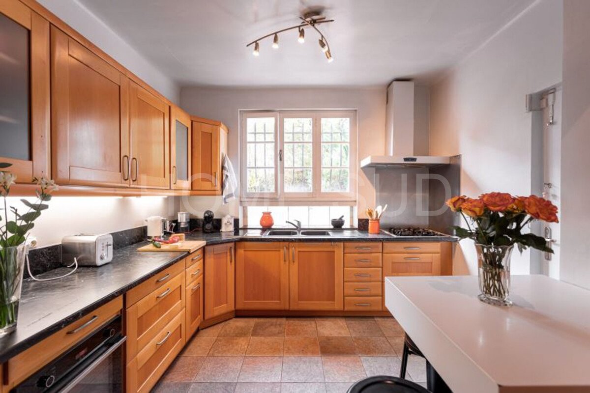 A kitchen with wooden cabinets and a vase of flowers on the counter