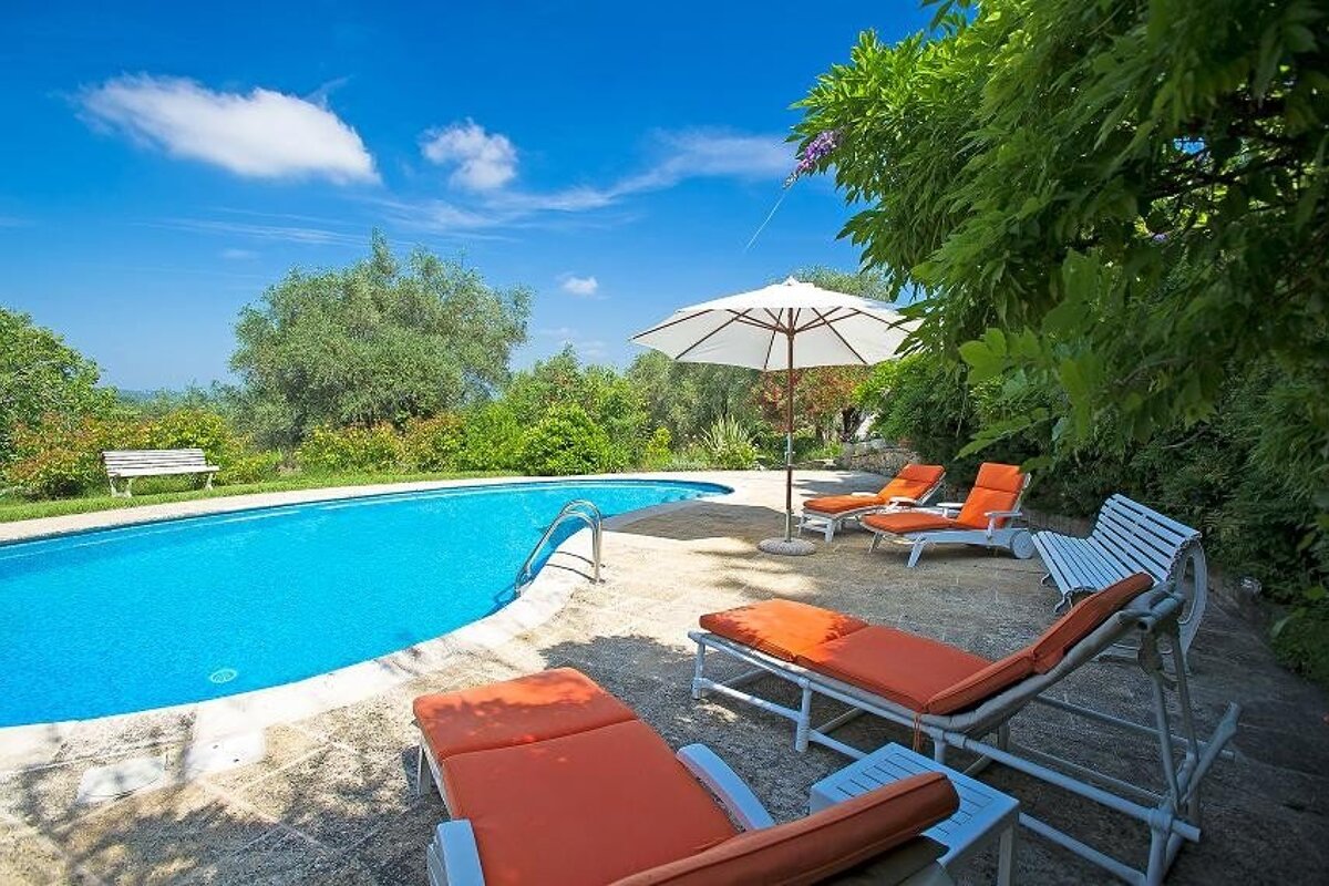 A swimming pool with orange lounge chairs and an umbrella