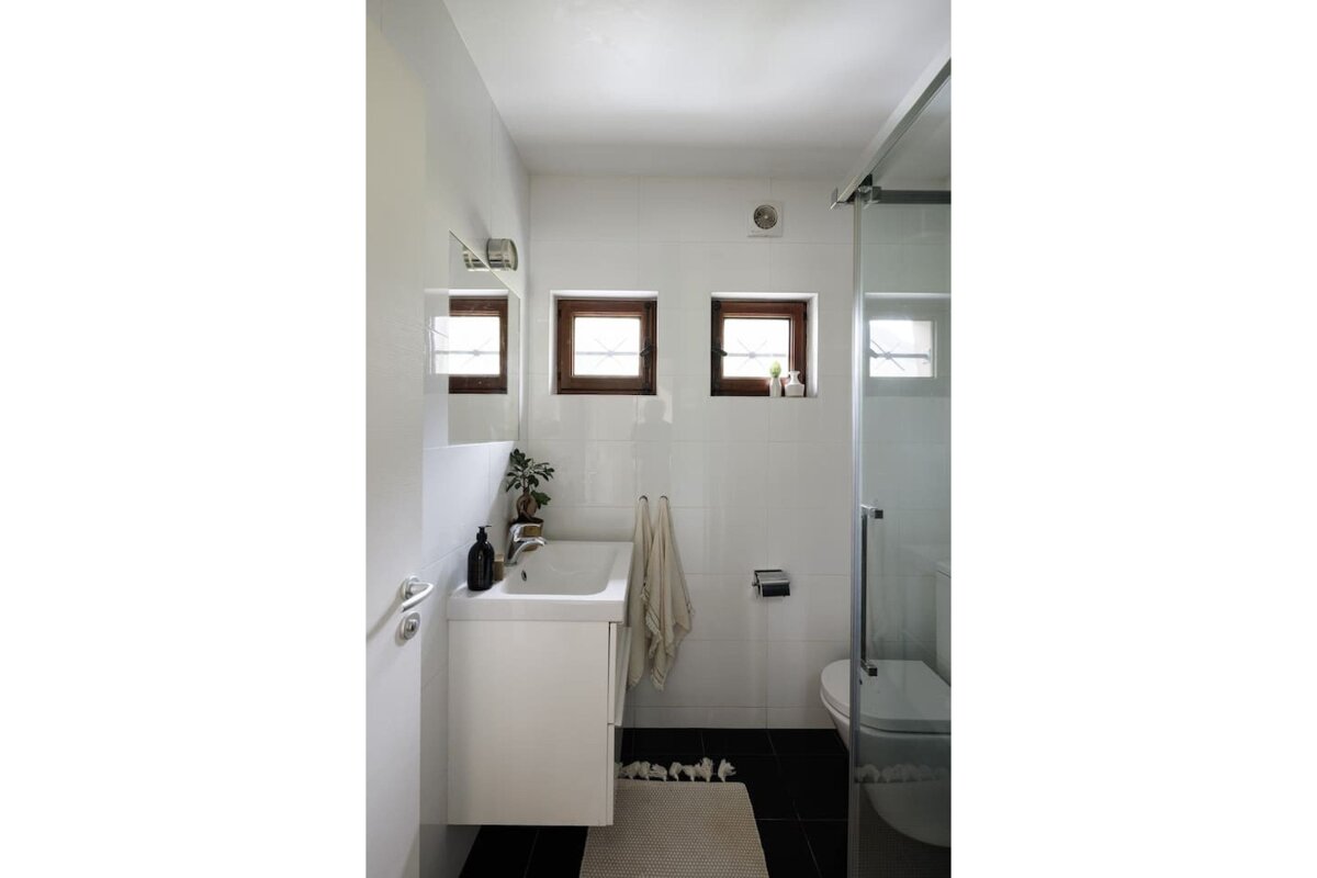 A bathroom with a sink a toilet and three windows