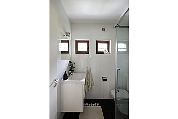 A bathroom with a sink a toilet and three windows