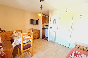 A dining room with a table and chairs and a flat screen tv