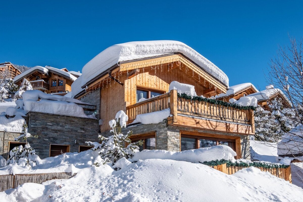 A snowy house with a balcony and a blue sky in the background