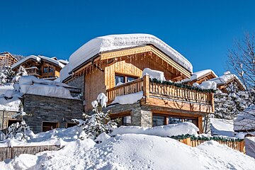 A snowy house with a balcony and a blue sky in the background