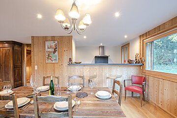 A dining room table with a bottle of wine on it