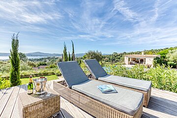 A bottle of champagne sits on a table next to two lounge chairs