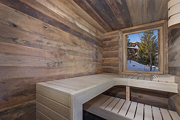 A wooden sauna with a window overlooking a snowy landscape