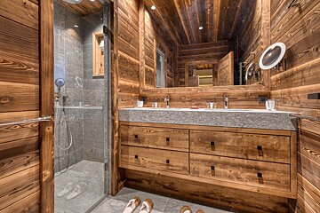 A bathroom with two sinks and a walk in shower