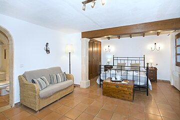 A bedroom with a couch and a trunk on the floor