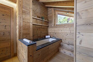 A bathtub in a wooden bathroom with a window