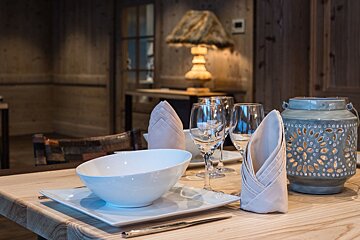 A wooden table with plates bowls glasses and a lantern