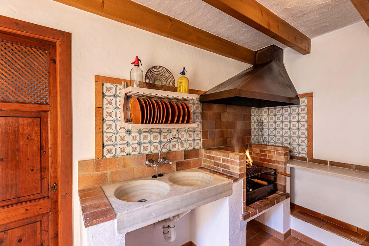 A kitchen with a sink and a shelf with plates on it