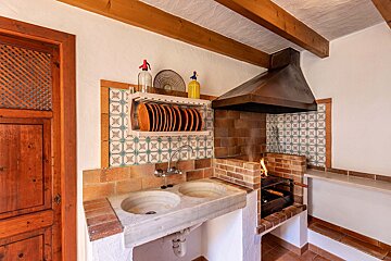 A kitchen with a sink and a shelf with plates on it