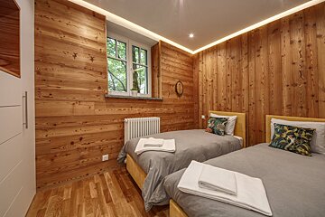 A bedroom with two beds and wood paneling on the walls