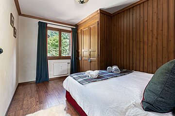 A bedroom with wood paneling and a bed with towels on it