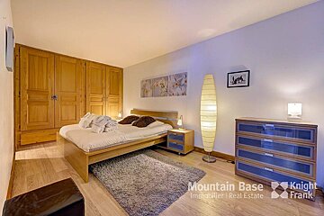A bedroom with a bed and a dresser from mountain base