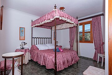 A bedroom with a four poster bed and pink curtains