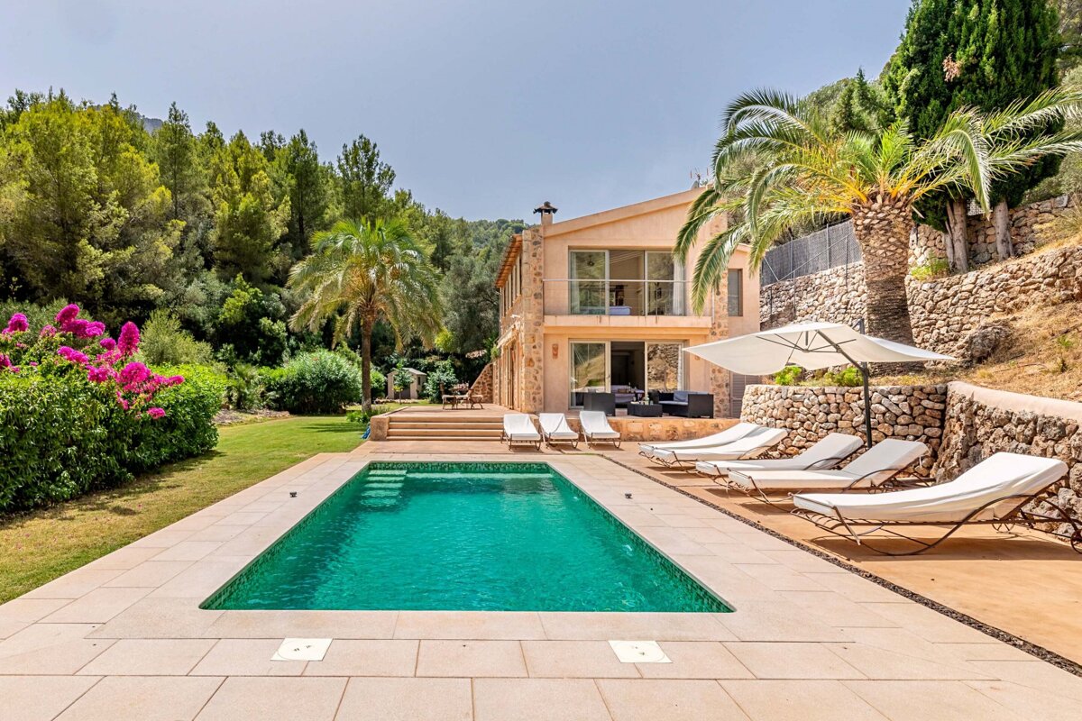A large swimming pool is surrounded by lawn chairs and umbrellas
