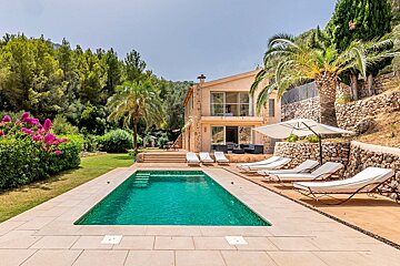A large swimming pool is surrounded by lawn chairs and umbrellas