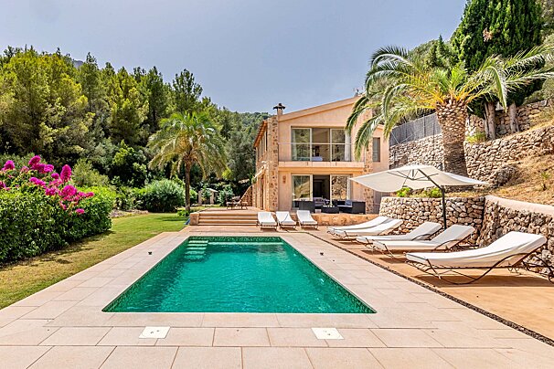 A large swimming pool is surrounded by lawn chairs and umbrellas