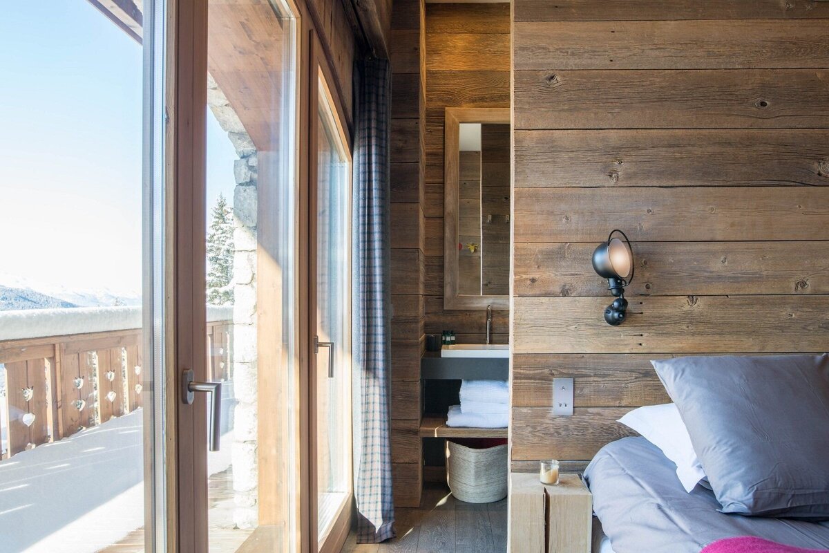 A bedroom with a wooden wall and a large window