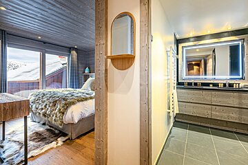 A bedroom with a bed and a bathroom with a mirror