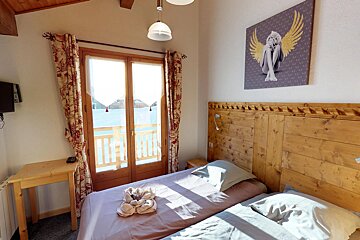 A bedroom with a painting of a woman with wings above the bed