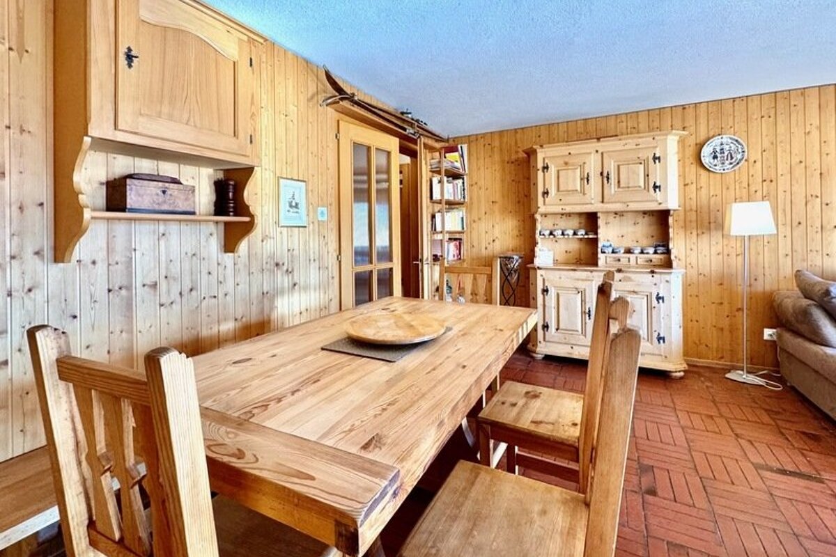 Rustic wooden dining room featuring pine paneled walls, a large wooden table with chairs, a hutch, and tiled flooring.
