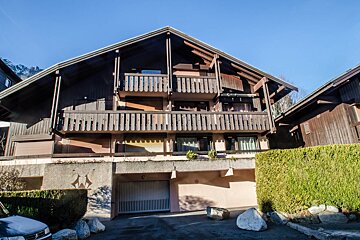 A large wooden house with a garage underneath it